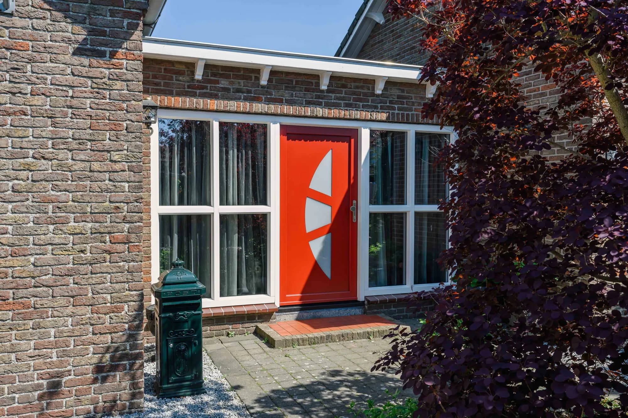 Rode voordeur met gebogen glas en witte kozijnen