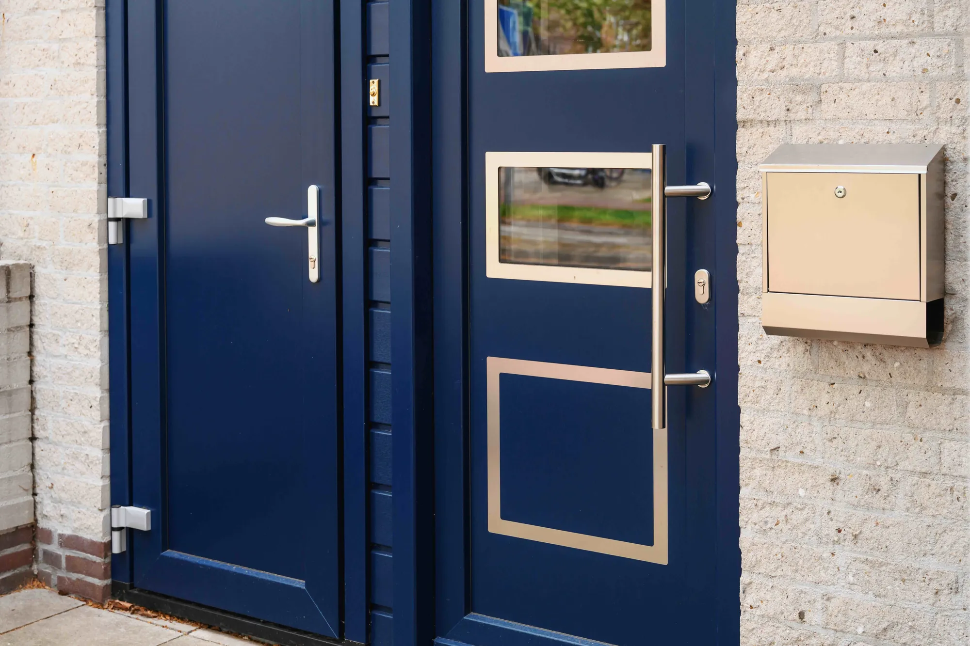 Detail van de donkerblauwe voordeur met lange handgreep