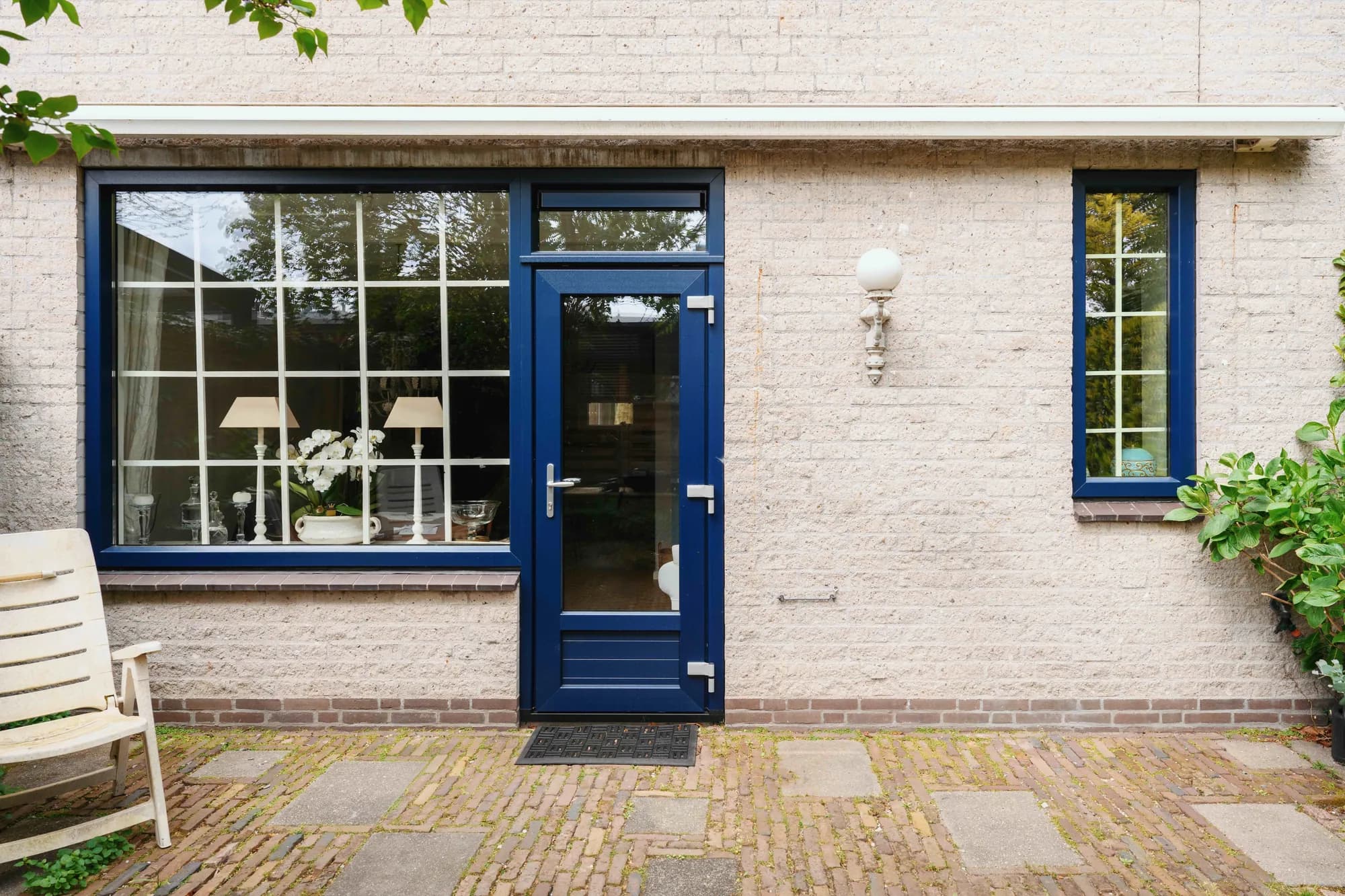 Brede gevel met donkerblauwe kozijnen in lichte baksteen