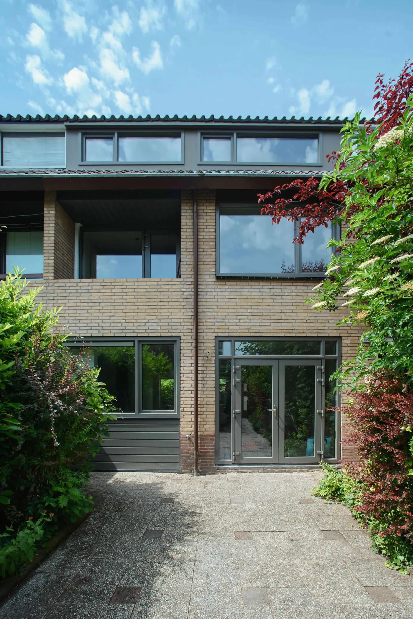 Achterzijde met donkere deur en kozijnen rond de binnenplaats