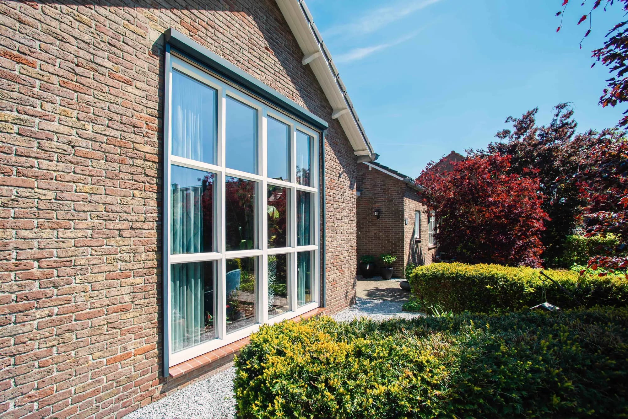 Wit zijraam in de bakstenen gevel van de woning